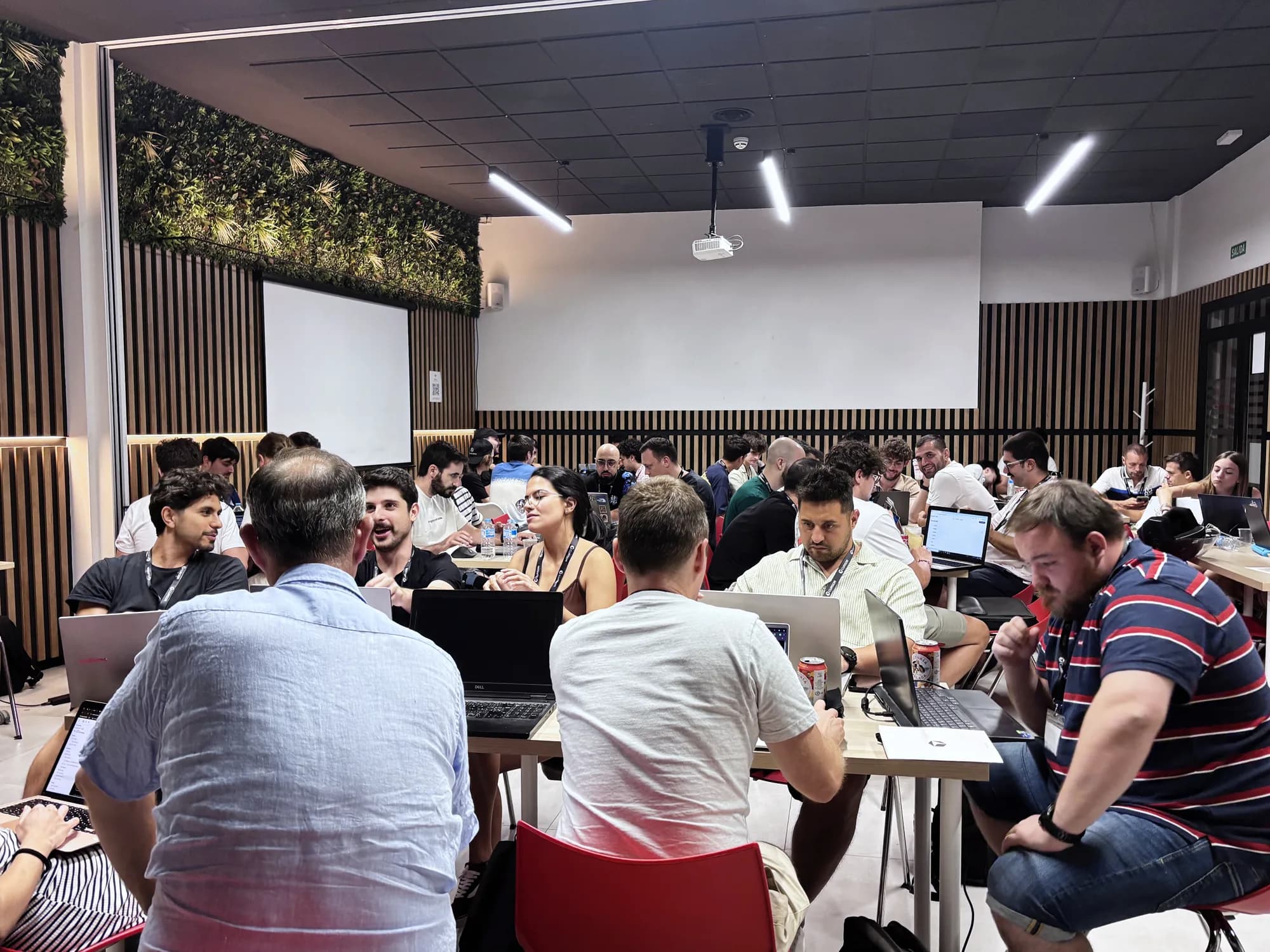 Teams coding around shared tables during Cursor Build Night Málaga